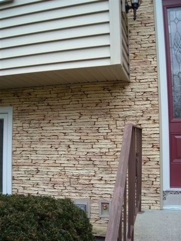 A house with tan stacked stonewall veneers on the front wall of a house