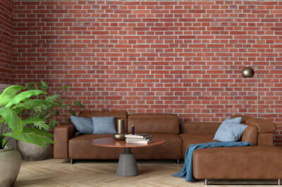 A living room with a brown coach and a brick accent wall.