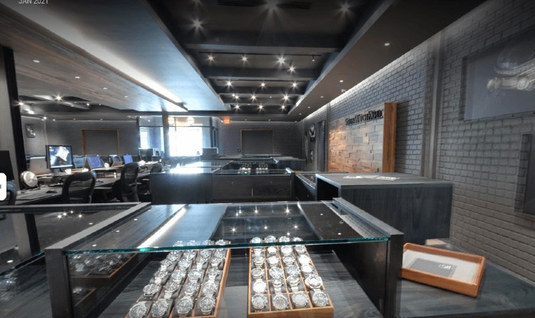 Overview of a Swiss watch store, featuring a wood panel accent wall contrasted against gray brick faux wall panels.