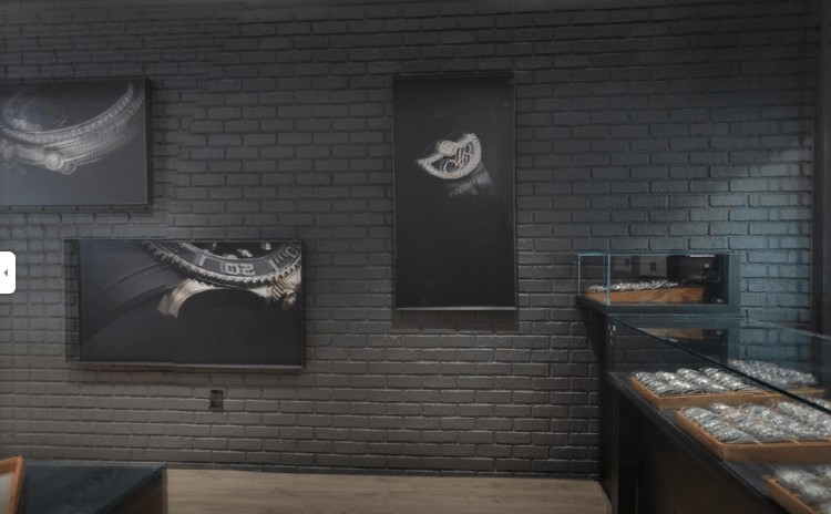 A Swiss watch store with display cases and large prints against a faux wall panel in gray brick