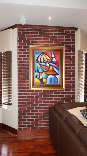 A colorful abstract painting placed over a red brick wall accent wall made of Texture Plus faux wall panels.