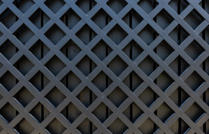 Black lattice paneling over a black wooden background.