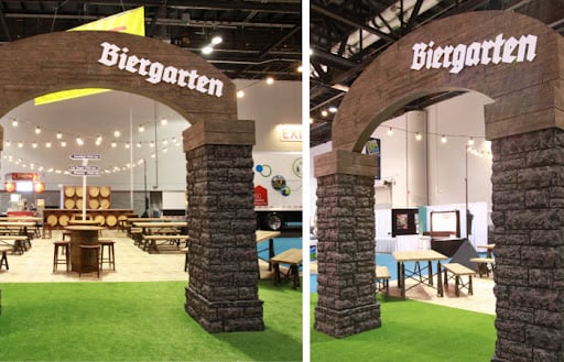 Large stone archway with the word Biergarten over a seating and drinking area of a convention center.