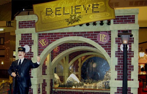 Trade show booth promoting the Polar Express. Built with faux red brick wall panels and featuring a miniature train set and a life-size model of the train conductor