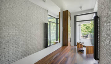Home corridor with long mirror, white brick wall, wooden floor and big window