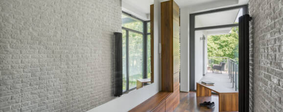 Home corridor with long mirror, white brick wall, wooden floor and big window
